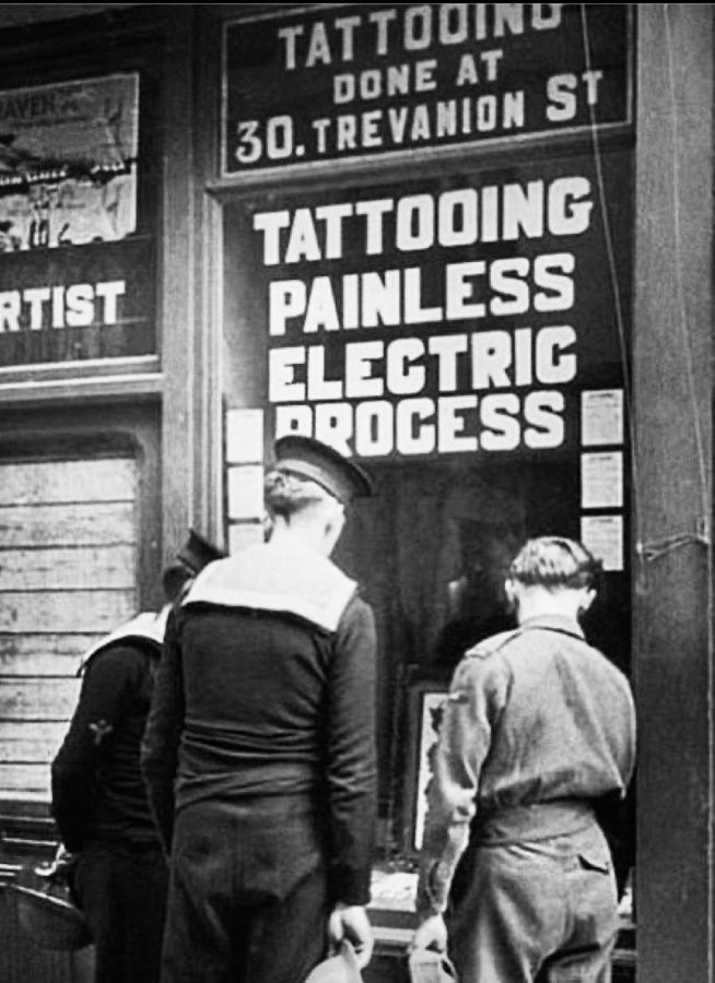 Marinheiros diante da vitrine de um estúdio de tatuagem